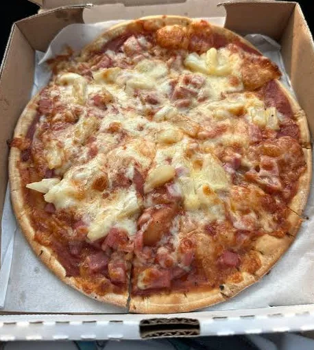Thin-crust pizza with diced ham and pineapple under melted cheese