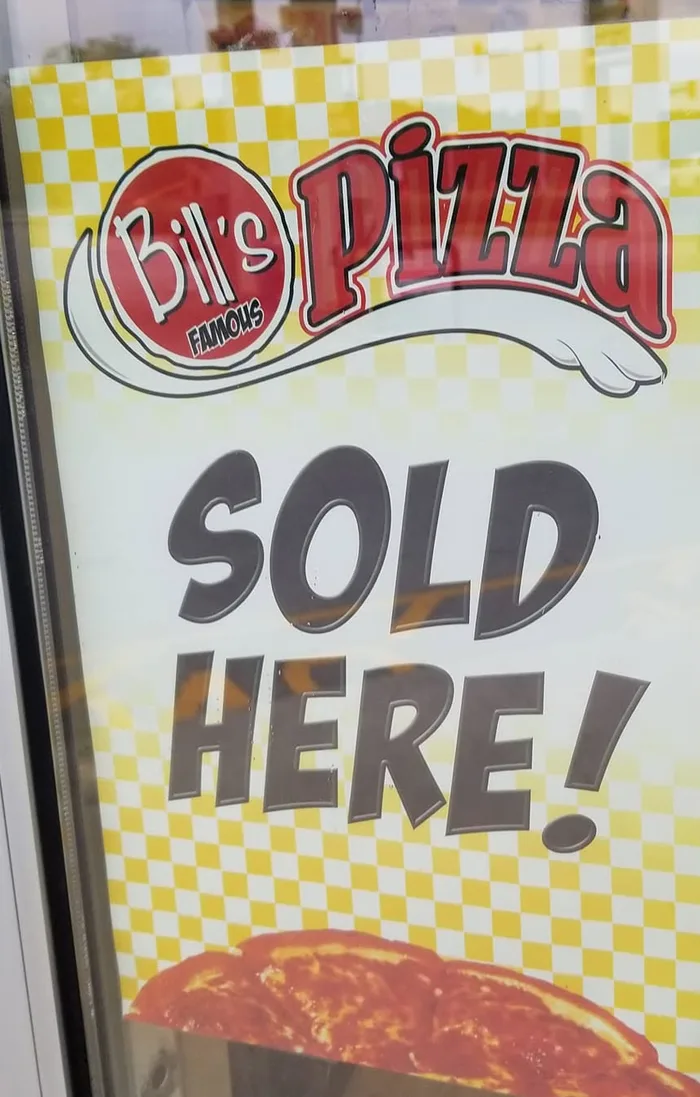 Yellow checkered 'Bill's Famous Pizza Sold Here!' poster in a store door window